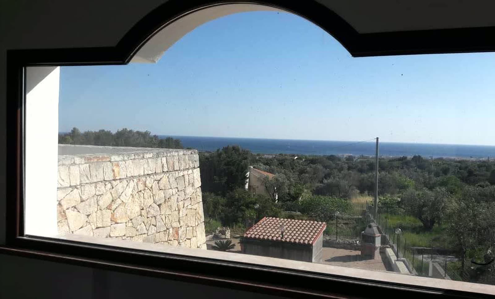 La finestra ad arco che guarda il mare e gli ulivi