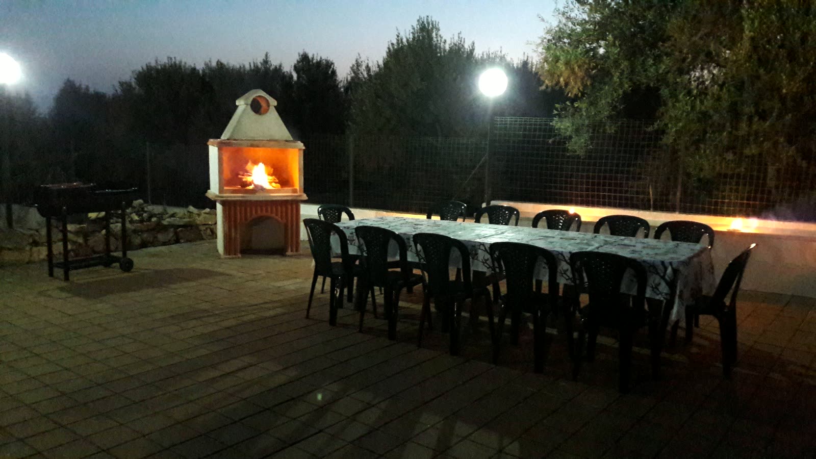 Il barbecue in muratura acceso e la tavola apparecchiata di sera