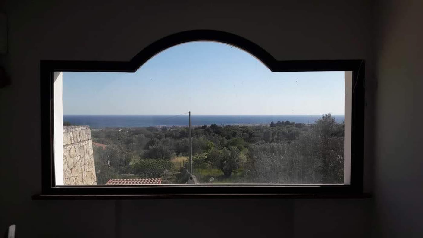 Finestra ad arco che guarda il mare fra gli ulivi