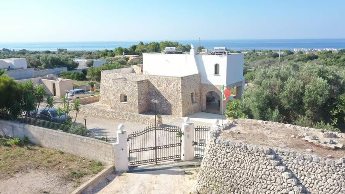 Il fronte della villa con il cancello e il mare all'orizzonte